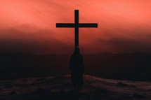 Silhouette of a man with a cross on top of the mountain
