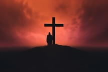Silhouette of a man standing in front of a cross.
