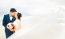 bride and groom kissing on a beach 