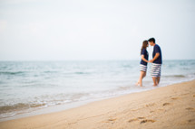 a couple holding hands on a beach 