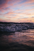 tide washing onto a beach at sunset 