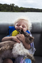 child hugging a dog on a boat