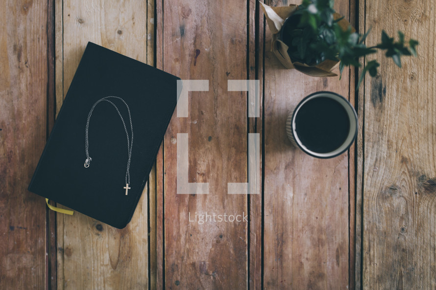 cross necklace on a Bible and coffee cup 