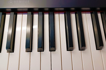 An up close photograph of an electric piano keyboard showing the white keys on the keyboard