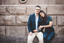 a couple sitting on a stone wall 