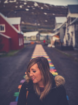 a woman standing in a small village street on a colorful path 