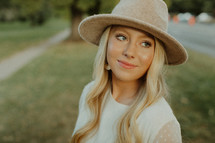 a blonde woman in a hat standing outdoors 