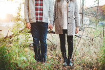 a couple holding hands in a field in fall 