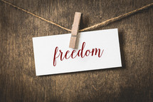 word freedom on white card stock hanging from a clothespin on a clothesline 