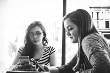 young women at a coffee shop for a Bible study using cellphones 