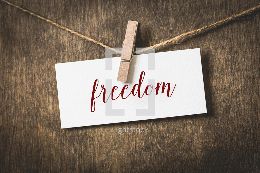 word freedom on white card stock hanging from a clothespin on a clothesline 