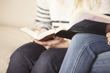 women sitting on a couch reading Bibles together. 