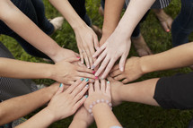 A group of girls are united as they put their hands together. 
