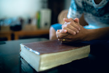 Hands clasped on a Bible praying