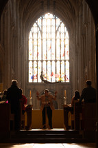 Church choir practice in a cathedral with light shining through a beautiful stained glass window