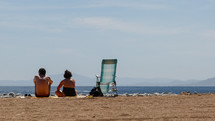 man and a woman sitting on a beach 