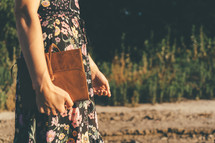 A girl walking down an abandon railroad track and holding her bible.