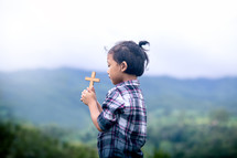 a child holding a cross outdoors 