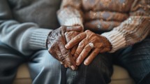 An older person is holding the hands of a younger person, showing a connection and support between generations.