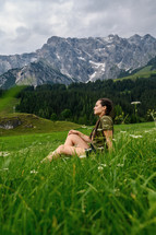a woman sitting on a green mountainside 