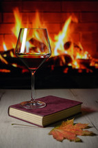 wine glass on a book in front of a fireplace 