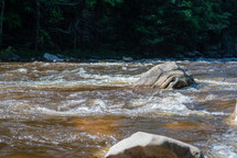 A fast-moving stream with a boulder in the middle
