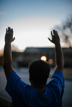 a man standing on a neighborhood street with arms raised 