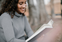 a young woman reading a Bible outdoors 