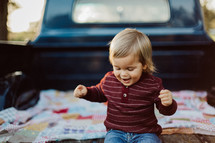 a toddler boy on a blanket in a truck bed 