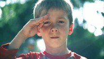 Boy saluting outside.