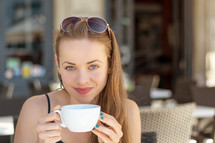 a young woman drinking coffee in a city 