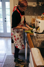 woman in a kitchen in an apron cutting an avocado 