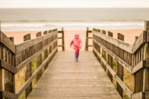 child running on a wood deck on a beach 