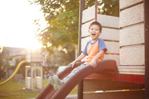 a boy child sliding down a slide on a playground 