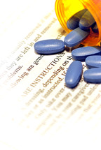Bright blue medicine tablets spilling from a prescription container lying on after-care instructions.