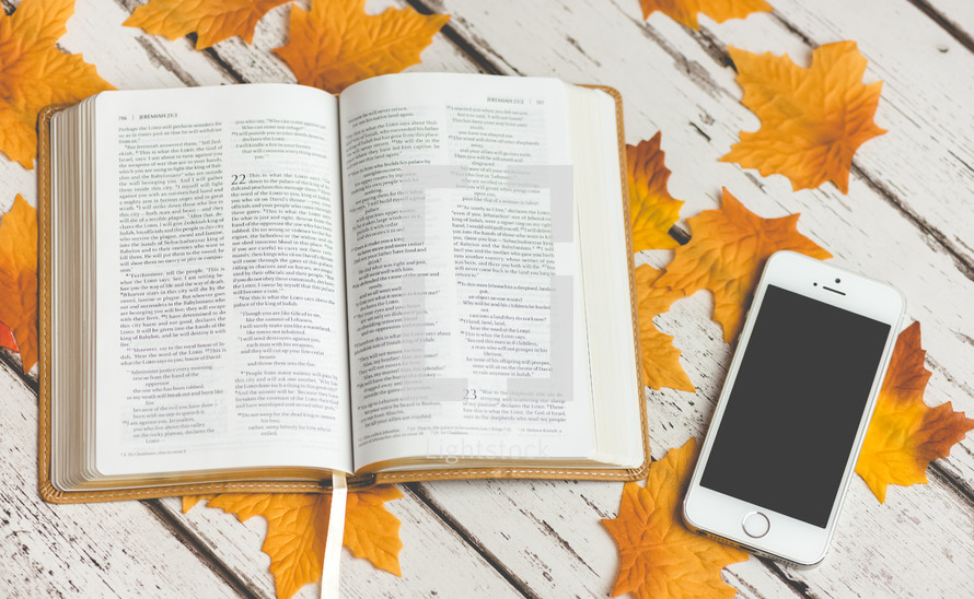 open Bible on fall leaves and iPhone 