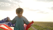 Cute little boy - American patriot kid running with national flag on open area countryside road.USA, 4th of July - Independence day, celebration. US banner, memorial Veterans, election, America, labor