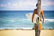 surfer holding a surfboard in front of ice blue water