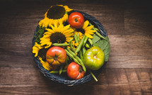 basket of tomatoes, green beans, and sunflowers 