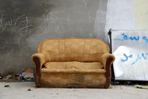 old couch and a graffiti covered wall in a refugee camp in Erbil, Iraq