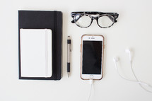 journal, glasses, pen, iPhone, earbuds 