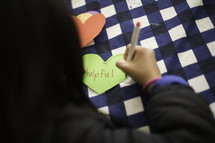 a child writing a word on a paper heart 