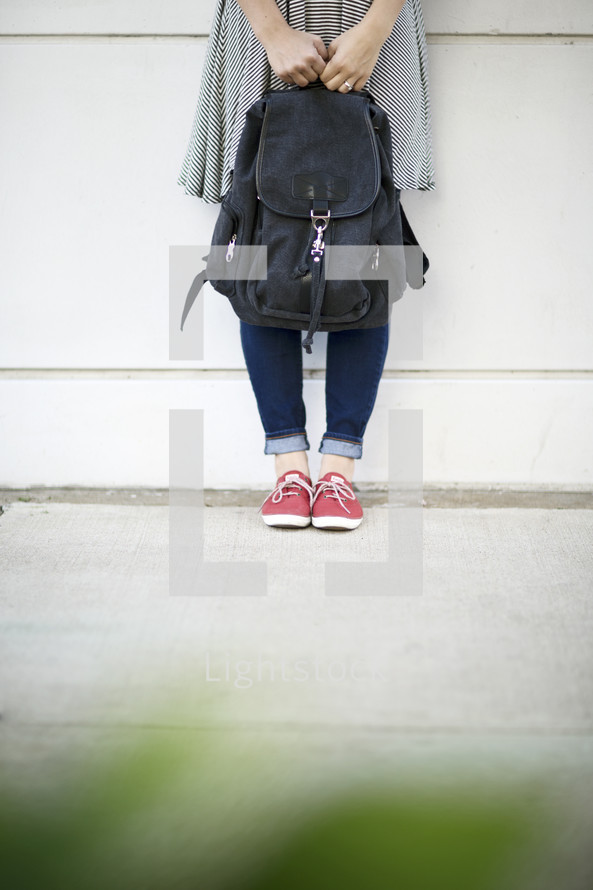 girl standing next to a book bag 