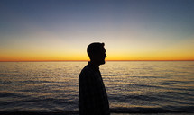side profile of a man on a beach at sunset 