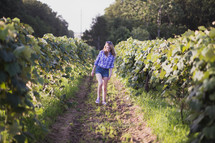 a young woman walking in a vineyard 