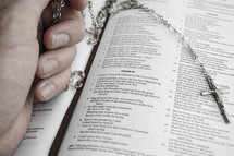holding a rosary over the pages of a Bible 