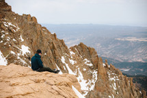 man sitting on top of a mountain 