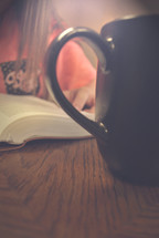 girl reading a Bible and coffee mug