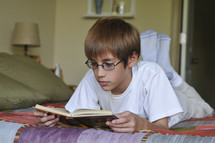 boy child reading on his bed 