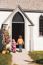 kids holding hands in front of a church door in fall 